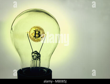 The coin of bitcoin glows inside the old lightbulb on a white background Stock Photo