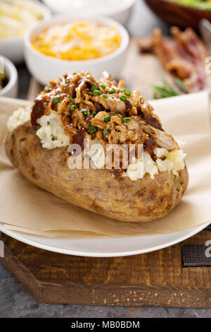 Baked potato with pulled pork and bbq sauce Stock Photo