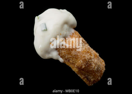 A pork scratching from a packet bought from a supermarket dipped in sor cream and chive. UK Stock Photo