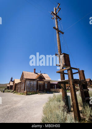 Telegraph pole and abandoned desolate buildings at Bodie State Historic Park, a former Wild West gold rush boomtown, nowadays a ghost town. Stock Photo