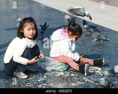 At Placa de Catalunya, Barcelona, Spain, 2 youngsters feeding pigeons Stock Photo