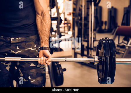 Sporty man holds barbell in gym close Stock Photo