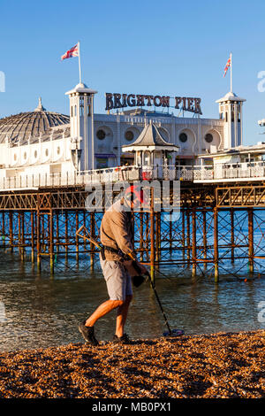 England, East Sussex, Brighton, Man with Metal Detector on Beach and Brighton Pier Stock Photo