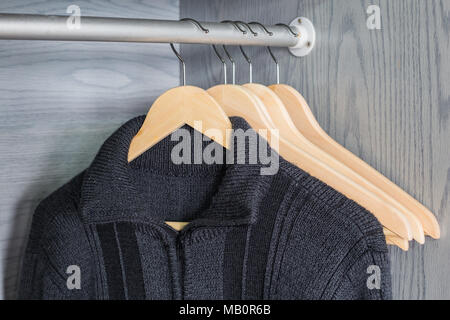A hanger with things. Knitted sweaters hang on hangers. Bright sweaters. Spring clothes. Stock Photo