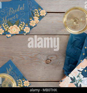 Blue floral rustic bridal shower table decorations with wine glass and gift bag on wooden background. Stock Photo