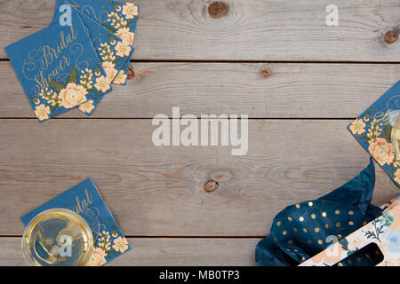 Blue floral rustic bridal shower table decorations with wine glass and gift bag on wooden background. Stock Photo