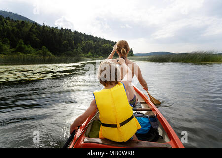 Mother and son paddling in a canoe on a picturesque lake Stock Photo