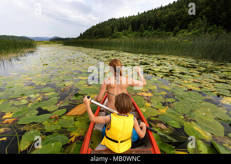 Mother and son paddling in a canoe on a picturesque lake Stock Photo