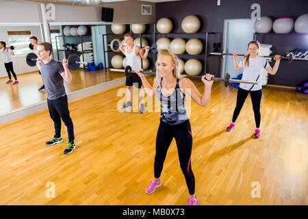 Focused team doing squat exercises with weights at fitness gym Stock Photo