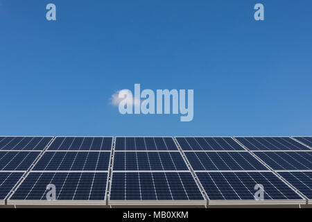 Solar panels against blue sky with one small cloud Stock Photo