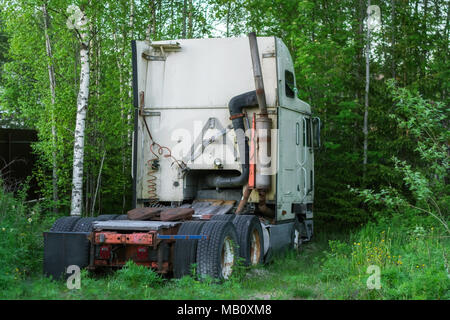 Old broken truck without a body, standing on an abandoned garden plot among the trees. Stock Photo