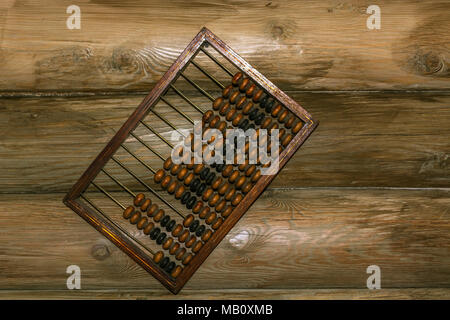 Old hand abacus hanging on a nail on the wall of wooden logs. Stock Photo