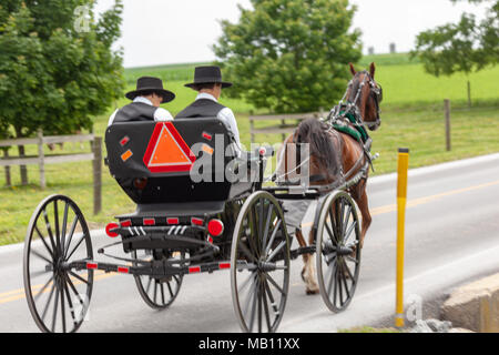 Bird-in-Hand, PA, USA - June 17, 2012: An open Amish buggy used for transportation used by two young men on a rural road in Lancaster County, PA. Stock Photo