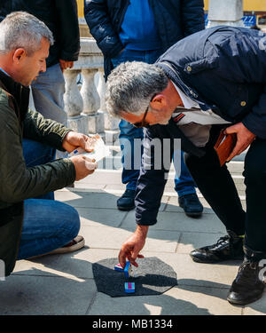 Con artists performing Shell Game scam to suspecting victims using matchsticks and small paper ball. The aim of the game is to predict in which box the ball will end up Stock Photo