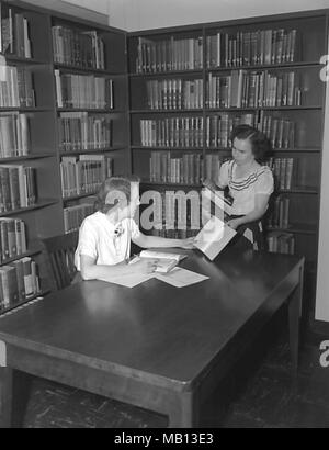 Two Centers for Disease Control (CDC) employees working in the campus library, Chamblee, Georgia, 1952. Image courtesy Centers for Disease Control (CDC). () Stock Photo