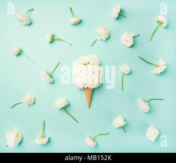 Flat-lay of waffle sweet cone with white buttercup flowers over light blue background, top view. Spring or summer mood concept Stock Photo