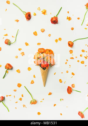 Flat-lay of waffle sweet cone with orange buttercup flowers over white background, top view, vertical composition. Spring or summer mood concept Stock Photo