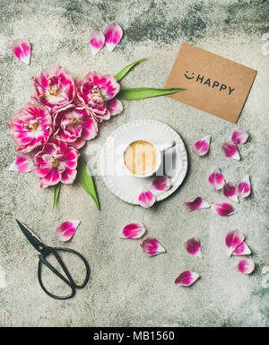 Spring morning concept. Flat-lay of cup of coffee surrounded with pink tulip flowers and sign happy over grey marble background, top view Stock Photo