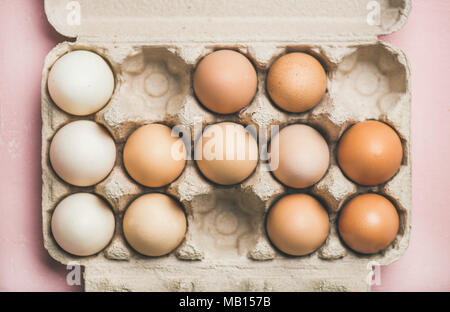 Easter holiday background. Flat-lay of natural colored eggs in box over light pink background, top view, horizontal composition. Greeting card concept Stock Photo