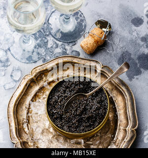 Black caviar in can on ice and champagne on concrete background close-up Stock Photo