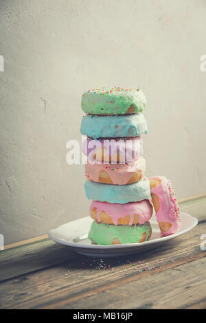 A stack of donuts on wooden table against the wall Stock Photo