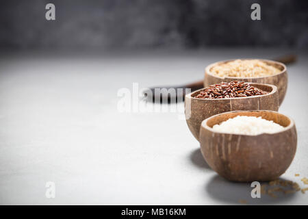 Assortment of different rice in bowls: Rice berry, Brown rice and Risotto rice on grey concrete background. Stock Photo