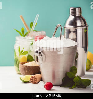 Metal ice bucket and fresh cocktails on blue background Stock Photo