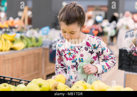 A girl in the store is picking apples. Stock Photo