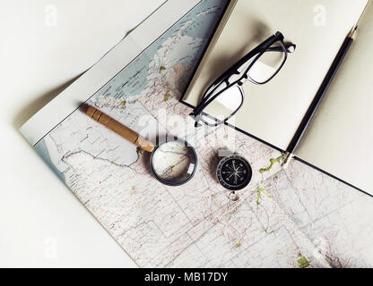 Stationery, travel accessories and vacation items. Vintage toned image. Flat lay. Top view. Map, notebook, magnifier, compass glasses and pencil Stock Photo