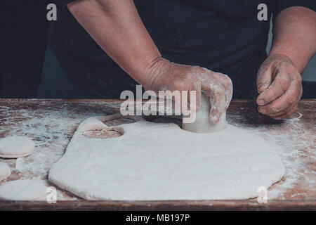 Granny squeezes a glass of a circle in a dough on the table 2018 Stock Photo