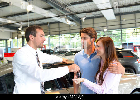 car salesman hands over the car key in the car dealership to customers Stock Photo