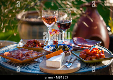Tapas style lunch with glasses of wine out on the patio garden table in beautiful sunlight Stock Photo