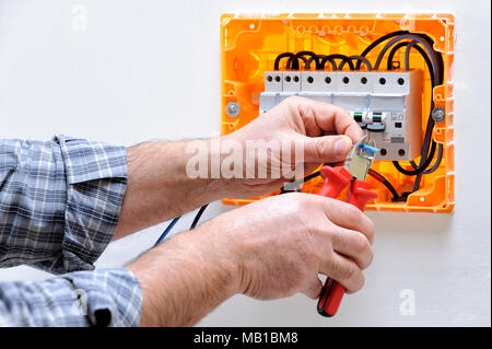 Electrician technician working on a residential electric panel, cuts the cable with a cable cutter Stock Photo