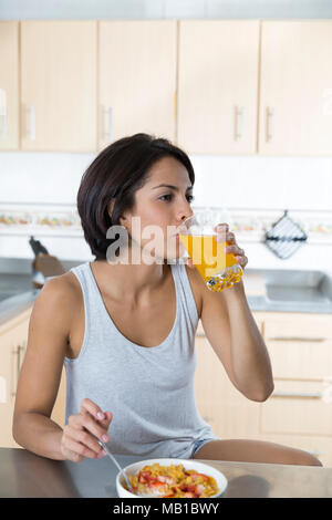 Smiling attractive woman having breakfast in kitchen interior Stock Photo