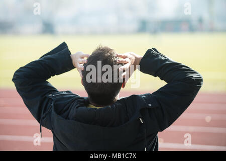 Back View of Young Man Sitting on Seat or Bleachers Sports Tribune and Cheering for His Favourite Team Stock Photo