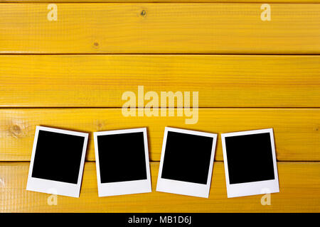 Four blank photo prints on a wood desk or table.  Space for copy. Stock Photo