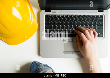 Contractor architect concept. Yellow hard hat helmet and laptop Stock Photo