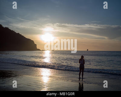 Woman observing the setting sun over the Pacific Ocean in San Francisco Stock Photo