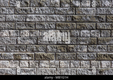 Brick wall made of grey and dirty white bricks. Front view. Stock Photo