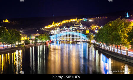 Tbilisi downtown. peace bridge made from glass, river Mtkvari, and famous ancient narikala fortress on hill. Night scene. Stock Photo