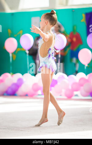 Little beautiful gymnast on carpet. Adorable gymnast participates in competitions in rhythmic gymnastics Stock Photo