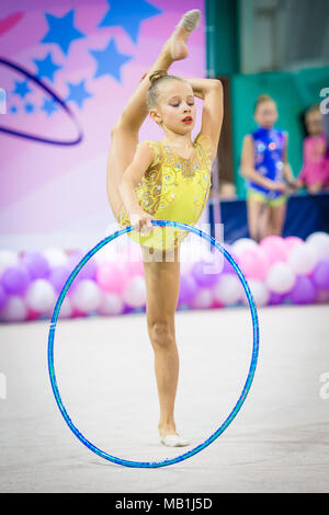 Little gymnast participates in competitions in rhythmic gymnastics Stock Photo