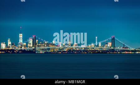 Verrazano Narrows Bridge gates the access to Upper New York Bay. Manhattan skyline rises behind the bridge. Stock Photo