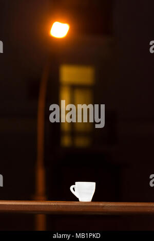 A white cup stands on a railing, against a background of a night street Stock Photo