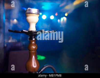 Hookah in clouds of smoke close-up on a blurred blue background with bokeh. Copy space. Stock Photo
