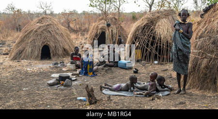 Omorate, Ethiopia - January 24, 2018: Women and children of the Mursi tribe resting in their village surrounded by the traditional houses of the Mursi Stock Photo