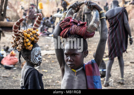 Omorate Ethiopia - January 24, 2018: Child from Mursi tribe posing for a portrait in his village with the traditional houses of the Mursi in Ethiopia. Stock Photo