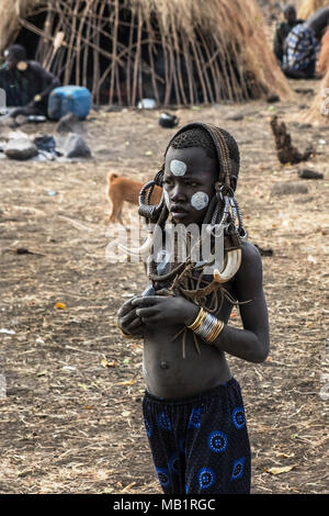 Omorate Ethiopia - January 24, 2018: Child from Mursi tribe posing for a portrait in his village with the traditional houses of the Mursi in Ethiopia. Stock Photo