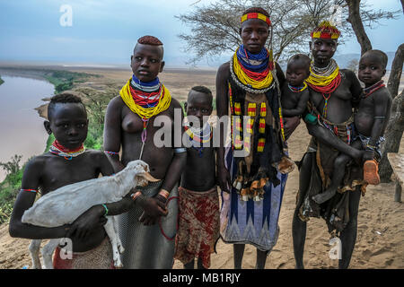 Omo Valley, Ethiopia - January 26, 2018: Unidentified Karo women and their children with Omo River in the background in Omo valley, Ethiopia. Stock Photo