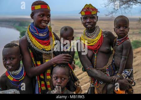 Omo Valley, Ethiopia - January 26, 2018: Unidentified Karo women and their children with Omo River in the background in Omo valley, Ethiopia. Stock Photo